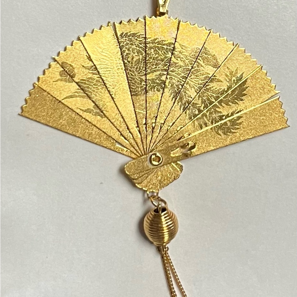 A vintage Asian fan pendant that is shiny, gold plated & opens & closes.